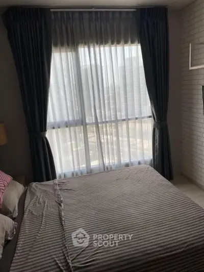 Cozy bedroom with large window and elegant curtains in modern apartment.