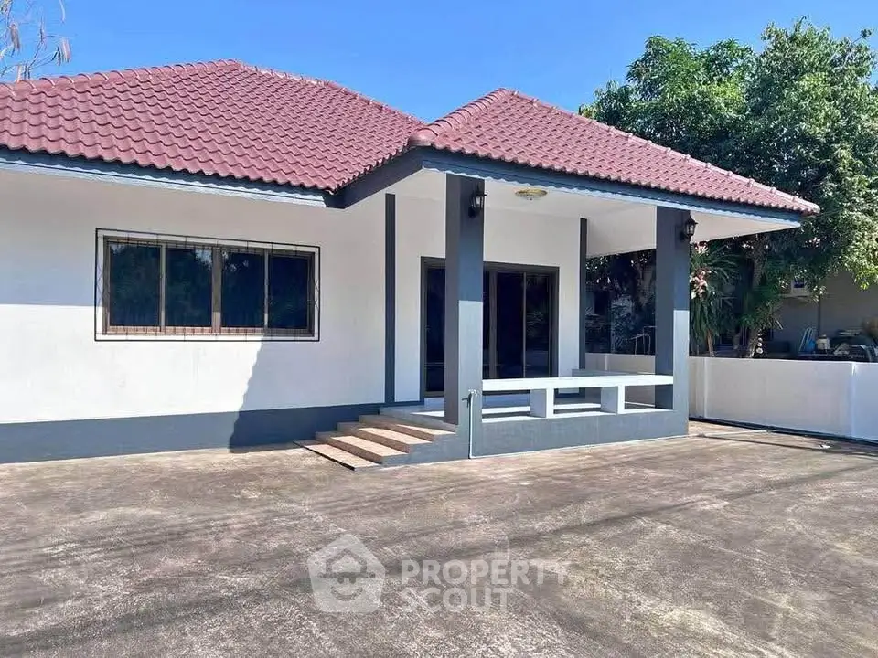 Charming single-story home with red-tiled roof and spacious front porch, perfect for family living.