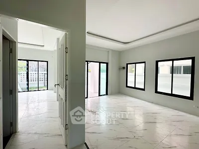Spacious modern living room with large windows and marble flooring in a contemporary home.
