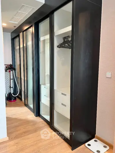 Modern walk-in closet with sliding glass doors and wooden flooring.
