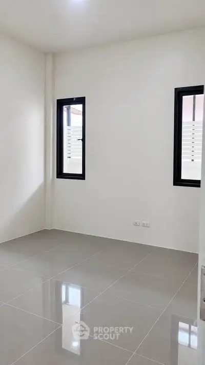 Spacious unfurnished room with tiled flooring and two windows, perfect for customization.