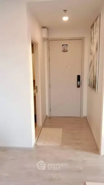 Modern apartment entrance with sleek wooden flooring and contemporary artwork.
