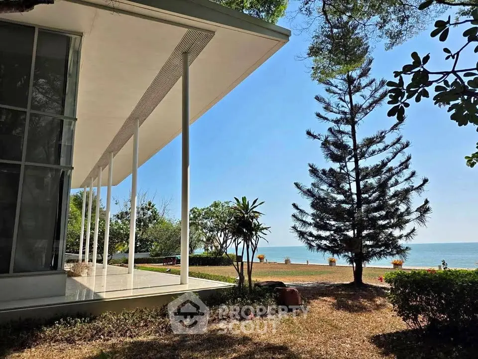 Stunning beachfront property with modern architecture and lush greenery, offering serene ocean views.