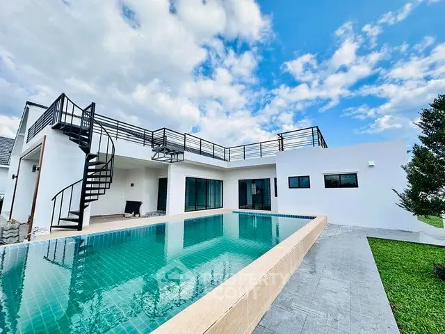 Stunning modern villa with rooftop terrace and private pool under a vibrant blue sky.