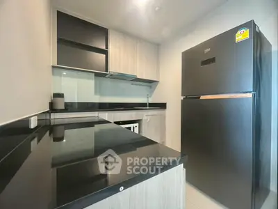 Modern kitchen with sleek black countertops and stainless steel appliances in a stylish apartment.