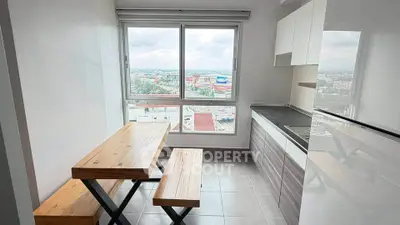 Modern kitchen with city view, featuring sleek cabinets and wooden dining set.