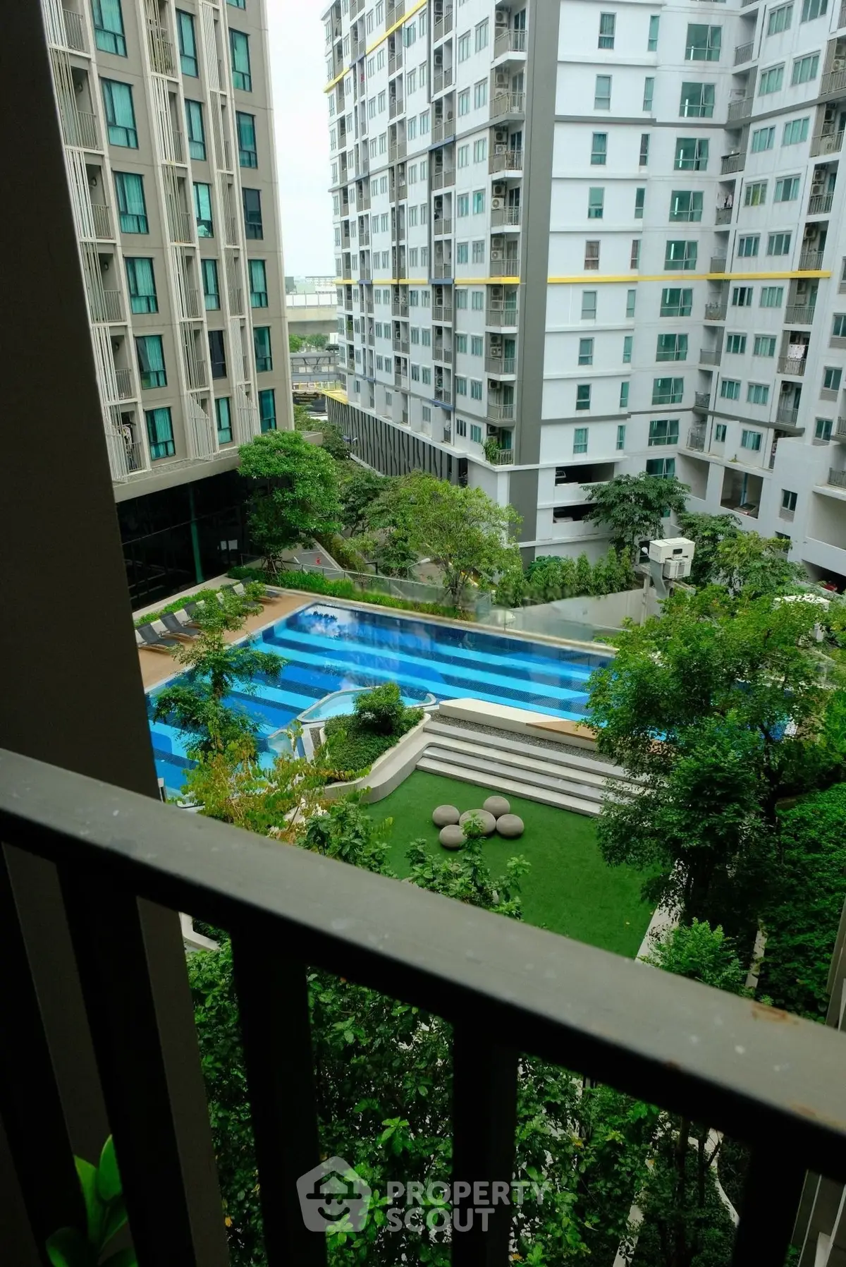 Stunning view of modern apartment complex with lush garden and inviting swimming pool.