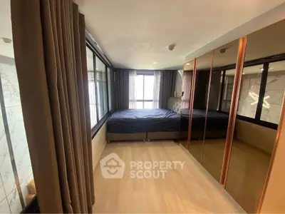 Modern bedroom with mirrored wardrobe and large windows offering natural light.