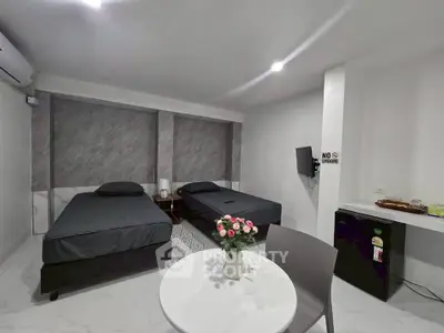 Modern bedroom with twin beds, air conditioning, and a small dining area, perfect for comfortable living.