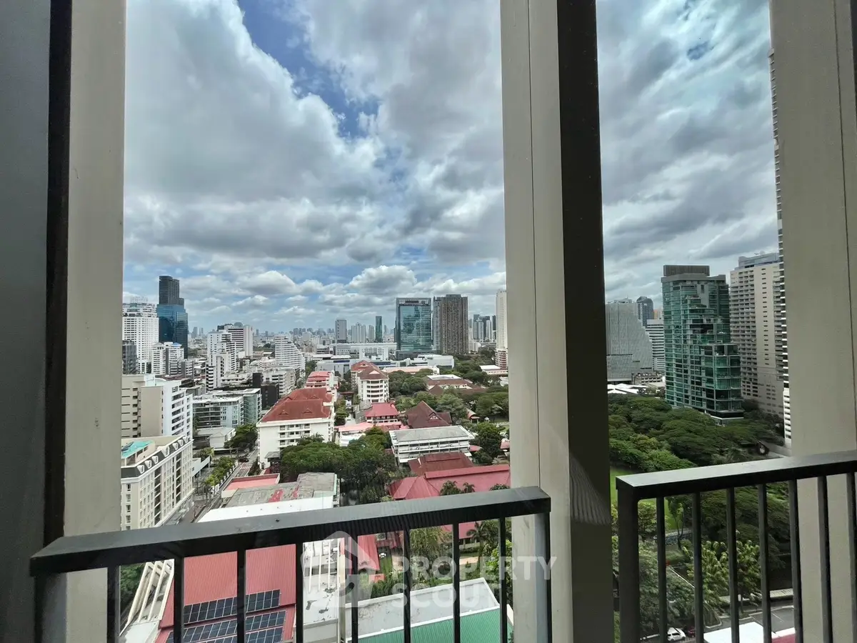 Stunning cityscape view from a high-rise balcony with lush greenery and urban skyline.