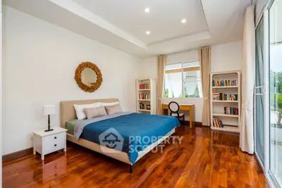 Spacious bedroom with elegant wooden flooring and natural light