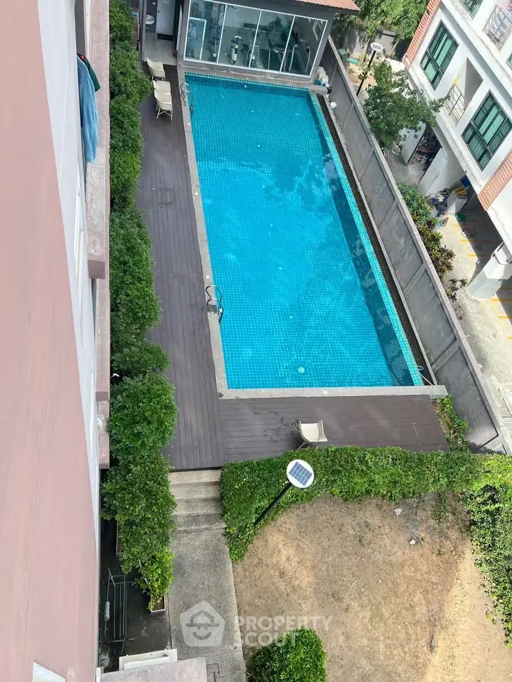 Stunning aerial view of a modern apartment pool surrounded by lush greenery, perfect for relaxation.