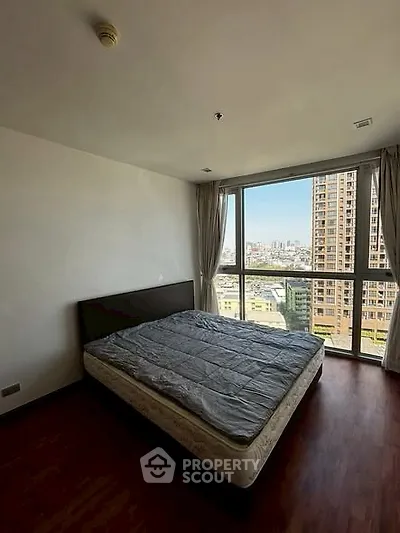 Spacious bedroom with large window offering stunning city views.