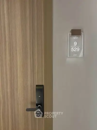 Modern apartment door with sleek electronic lock and room number display.