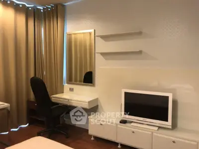Modern bedroom with TV, desk, and mirror in cozy apartment