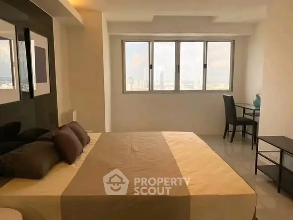Spacious bedroom with city view and modern furnishings in high-rise apartment.
