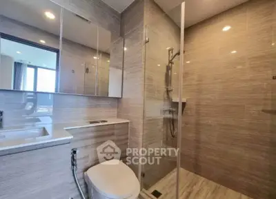 Modern bathroom with glass shower and sleek fixtures in luxury apartment.