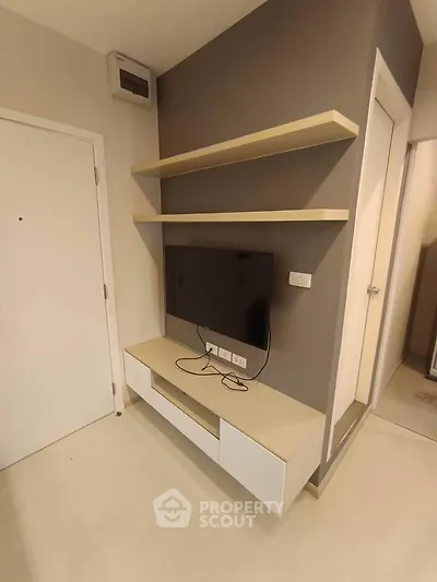 Modern living room with wall-mounted TV and sleek shelving in a stylish apartment.