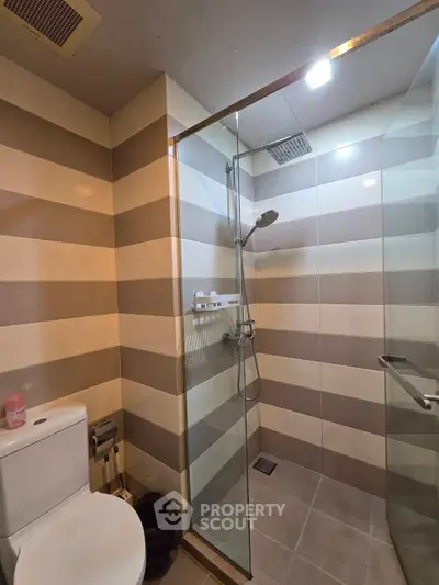 Modern bathroom with striped tiles and glass shower enclosure