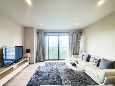 Spacious living room with modern decor and large window offering natural light and greenery view.