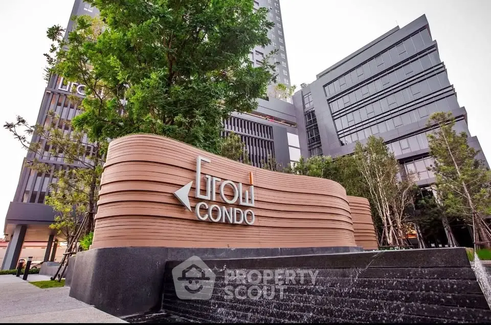 Modern condo building exterior with lush greenery and stylish signage.