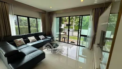 Spacious living room with large windows and garden view, featuring modern furniture and elegant decor.