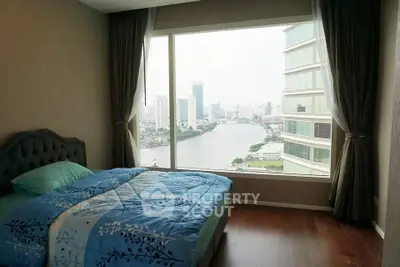 Stunning bedroom with panoramic city and river view, featuring elegant decor and large window.