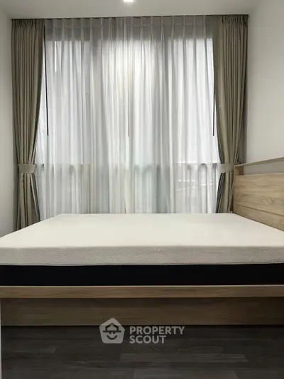 Modern bedroom with large window and elegant curtains, featuring a minimalist bed design.