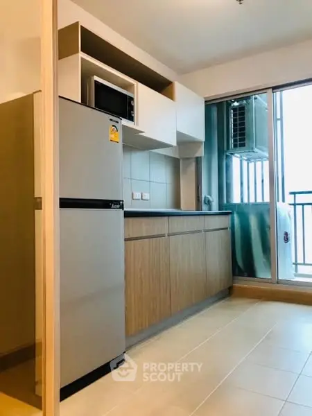 Modern kitchen with sleek cabinets and balcony access in urban apartment.