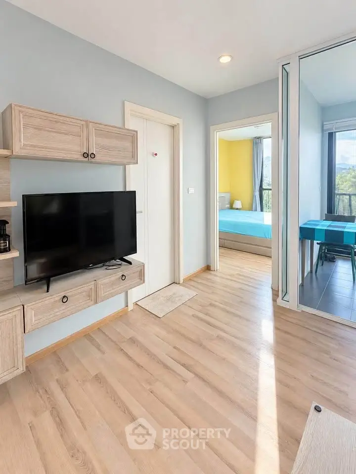 Modern living room with TV and view into a bright bedroom