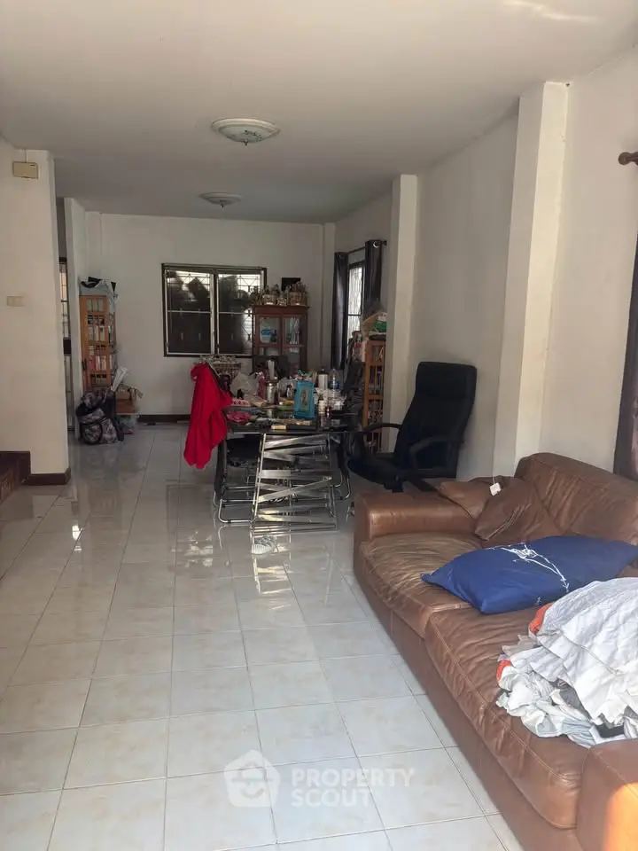 Spacious living room with tiled floor, cozy sofa, and dining area, perfect for family gatherings.