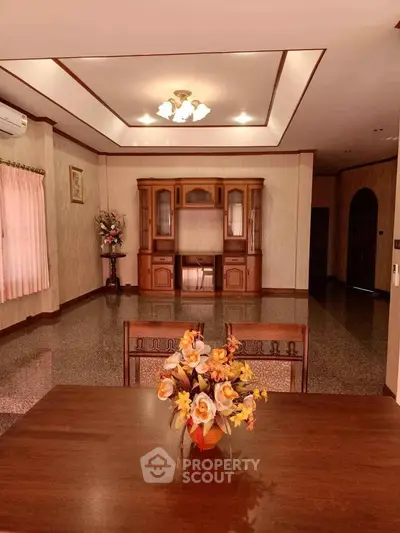 Spacious living room with elegant wooden furniture and decorative ceiling lights.