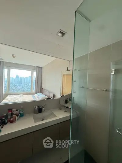 Modern bathroom with city view from adjacent bedroom, featuring sleek vanity and glass shower.