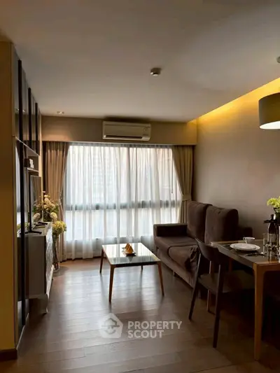 Modern living room with elegant decor and large window, featuring a cozy dining area and stylish furniture.