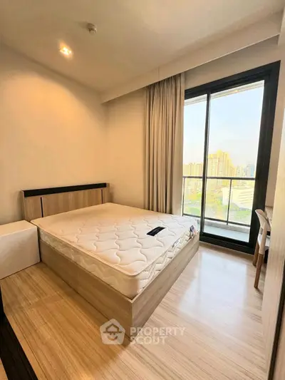 Modern bedroom with large window and city view, featuring a comfortable bed and sleek wooden flooring.