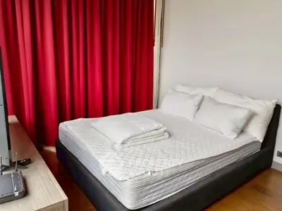 Cozy bedroom with red curtains and modern furnishings, perfect for relaxation.