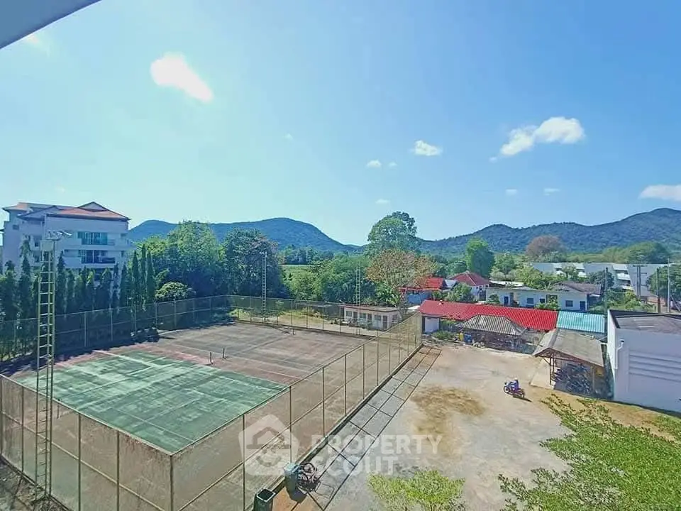 Scenic view of tennis court with mountain backdrop in serene residential area.