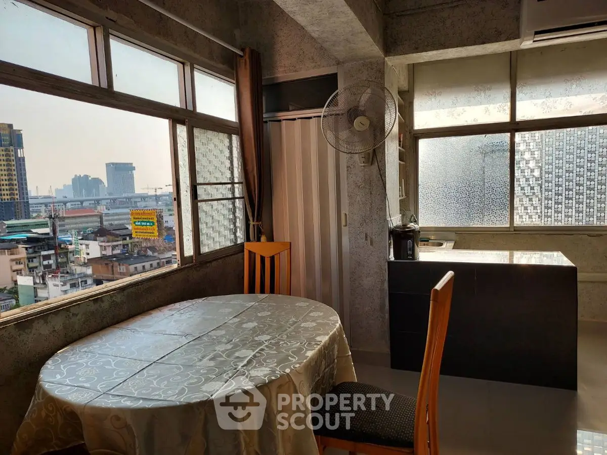 Spacious urban dining area with large windows offering city views, featuring a round table and modern decor.