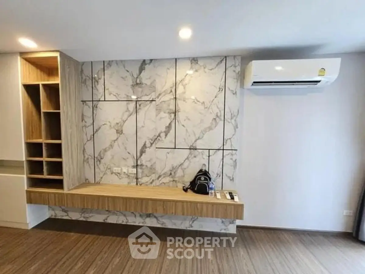 Modern living room with marble accent wall and built-in shelving, featuring sleek air conditioning unit.