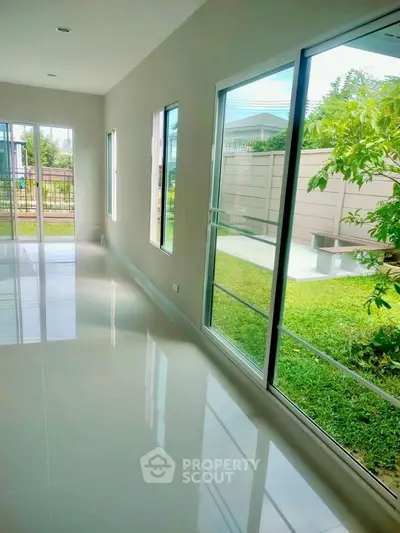 Bright living room with large windows overlooking a lush garden, perfect for natural light lovers.
