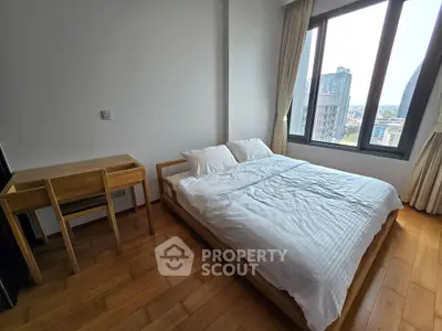 Bright bedroom with wooden flooring and large window offering city views