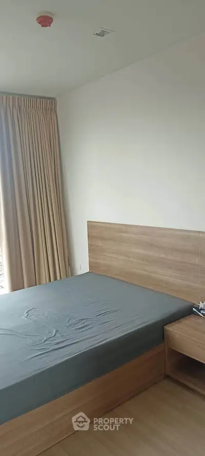 Modern bedroom with wooden furniture and large window for natural light.