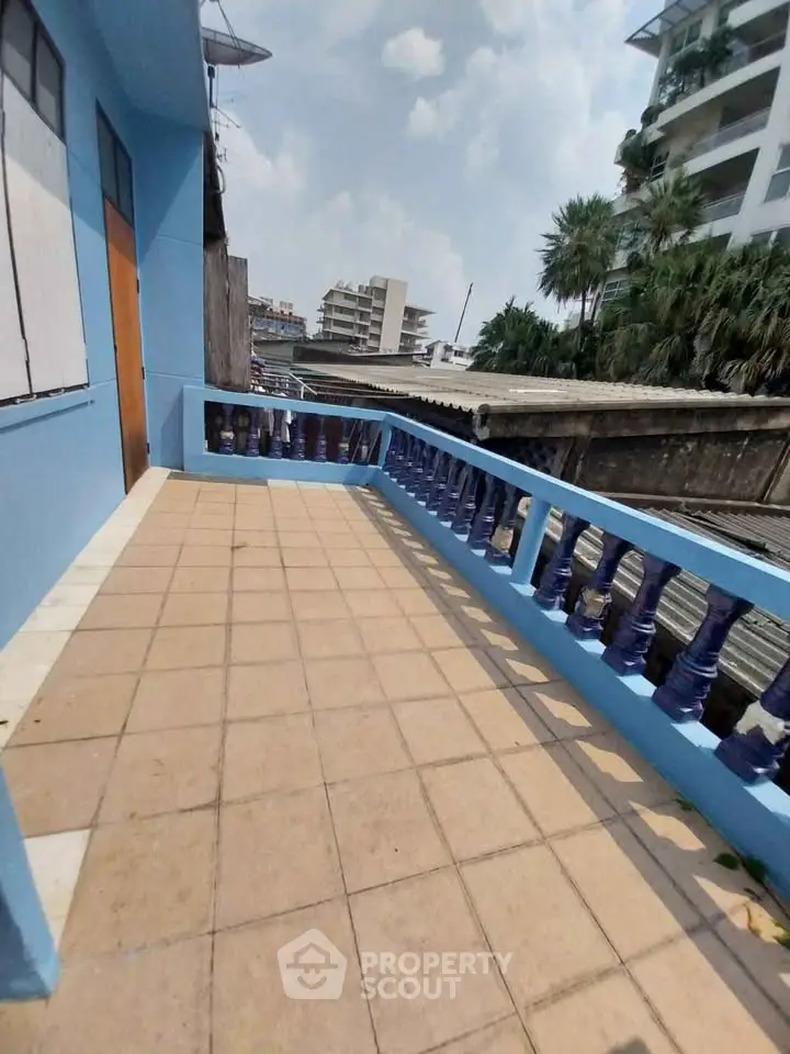 Spacious balcony with blue railings offering urban views in a residential building.