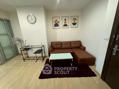 Modern living room with stylish brown sofa, abstract art, and sleek glass desk.