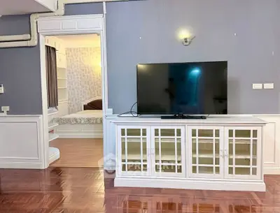 Spacious living room with elegant TV stand and view into cozy bedroom