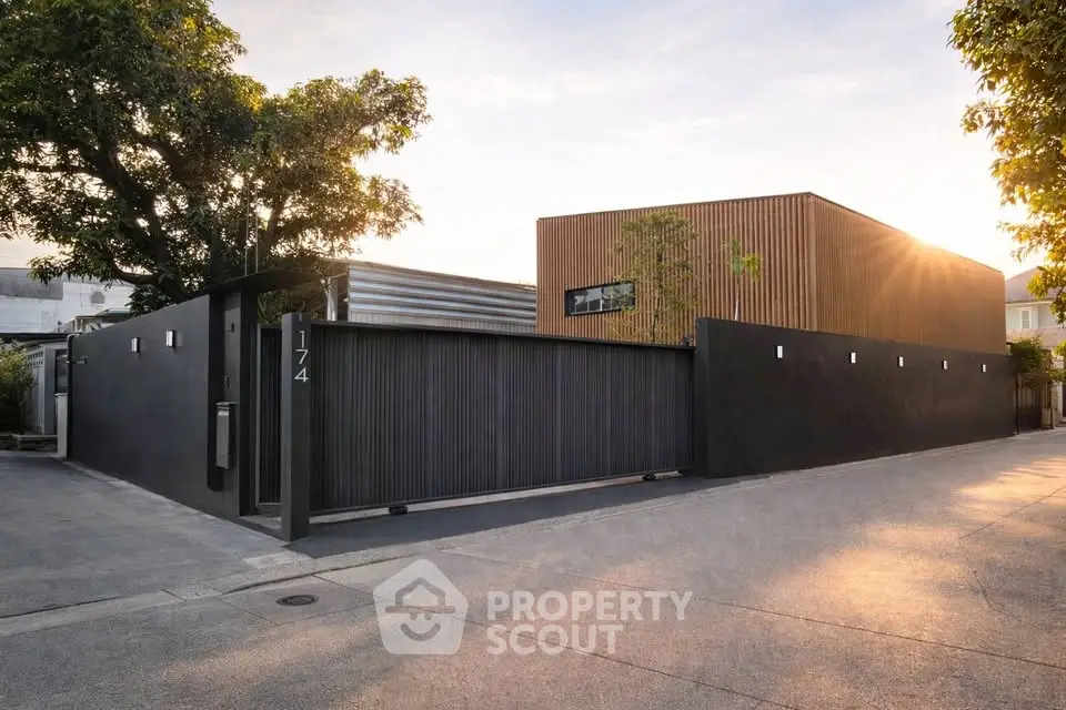 Modern minimalist house exterior with sleek black fence and wooden accents at sunset.
