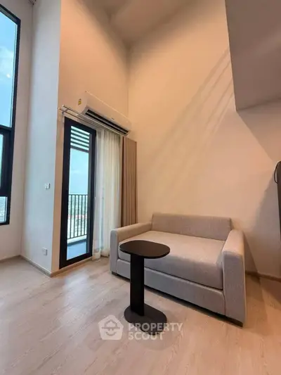 Modern living room with high ceiling and balcony access in a stylish apartment.