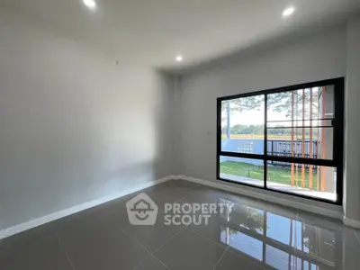 Spacious empty room with large window offering scenic view, perfect for customization.