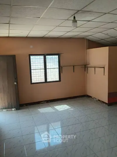 Spacious empty room with tiled floor and natural light, ideal for customization.