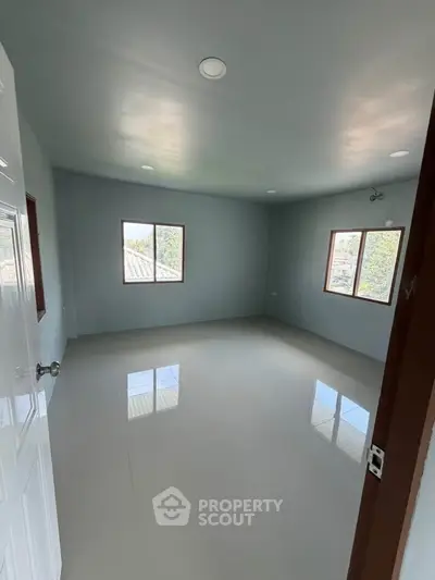 Spacious empty room with large windows and glossy floor, perfect for customization.